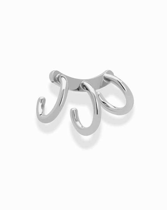 The *Preorder* Eli Tripple Helix Ear Cuff by Mod + Jo features three curved hooks on a sleek base, offering a stylish, no-piercing look. Shown in silver on a white background and available in both gold and silver finishes.