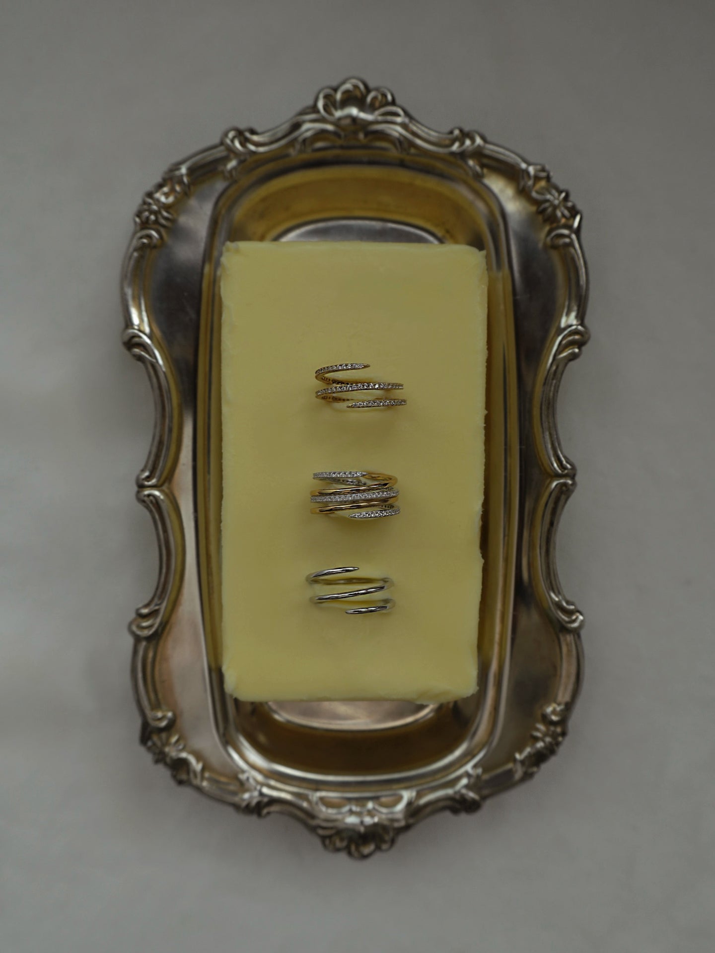 Showcasing three pave spiral rings (Greer ring) in gold and silver tones, displayed on a decorative tray. Jewelry display.