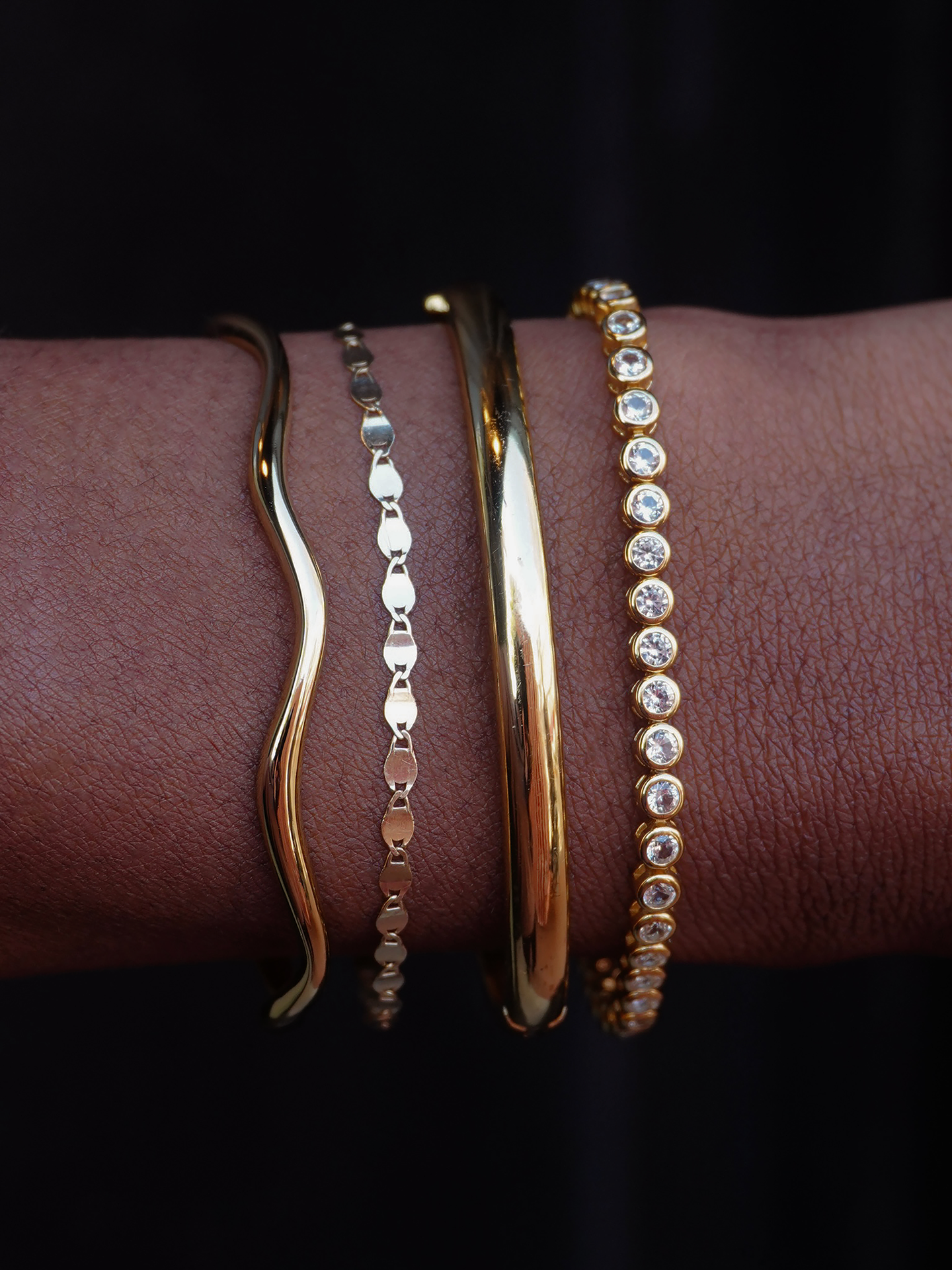 Close-up of Tate Dome Bangle worn with other gold bracelets showcasing jewelry styling and wrist adornment.