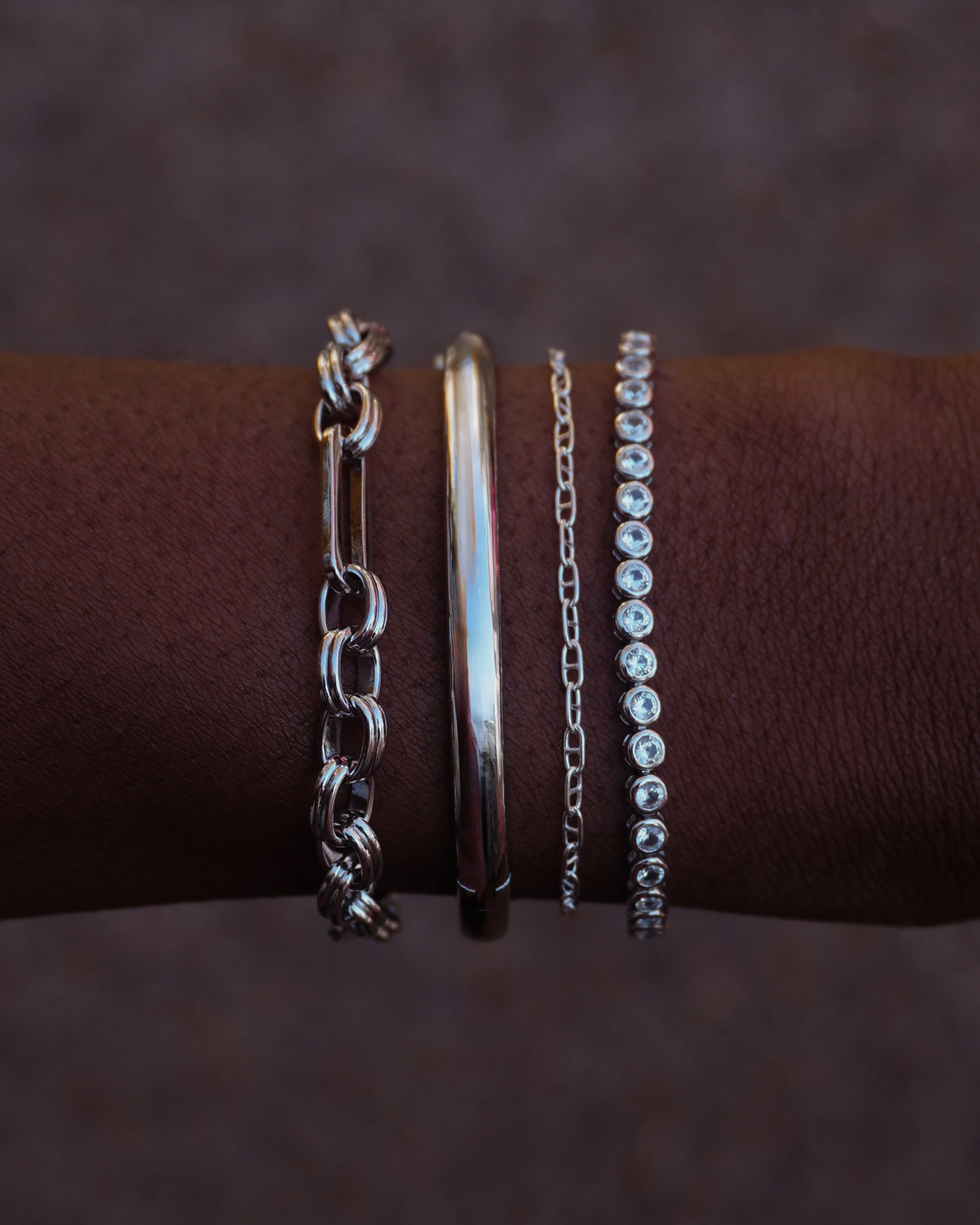 Penelope chain bracelet shown with other silver bracelets on a wrist, showcasing layering options.