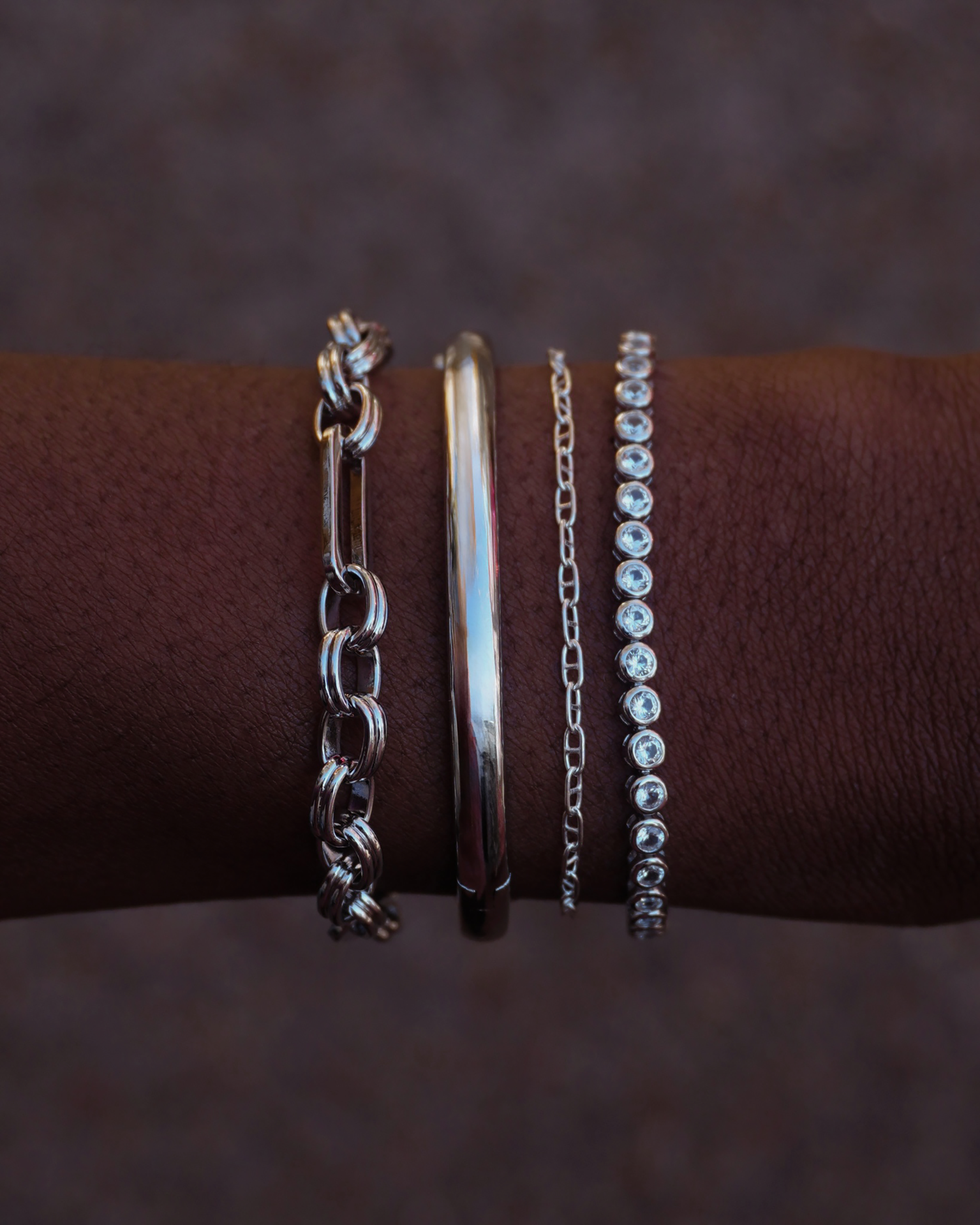 Penelope chain bracelet shown with other silver bracelets on a wrist, showcasing layering options.