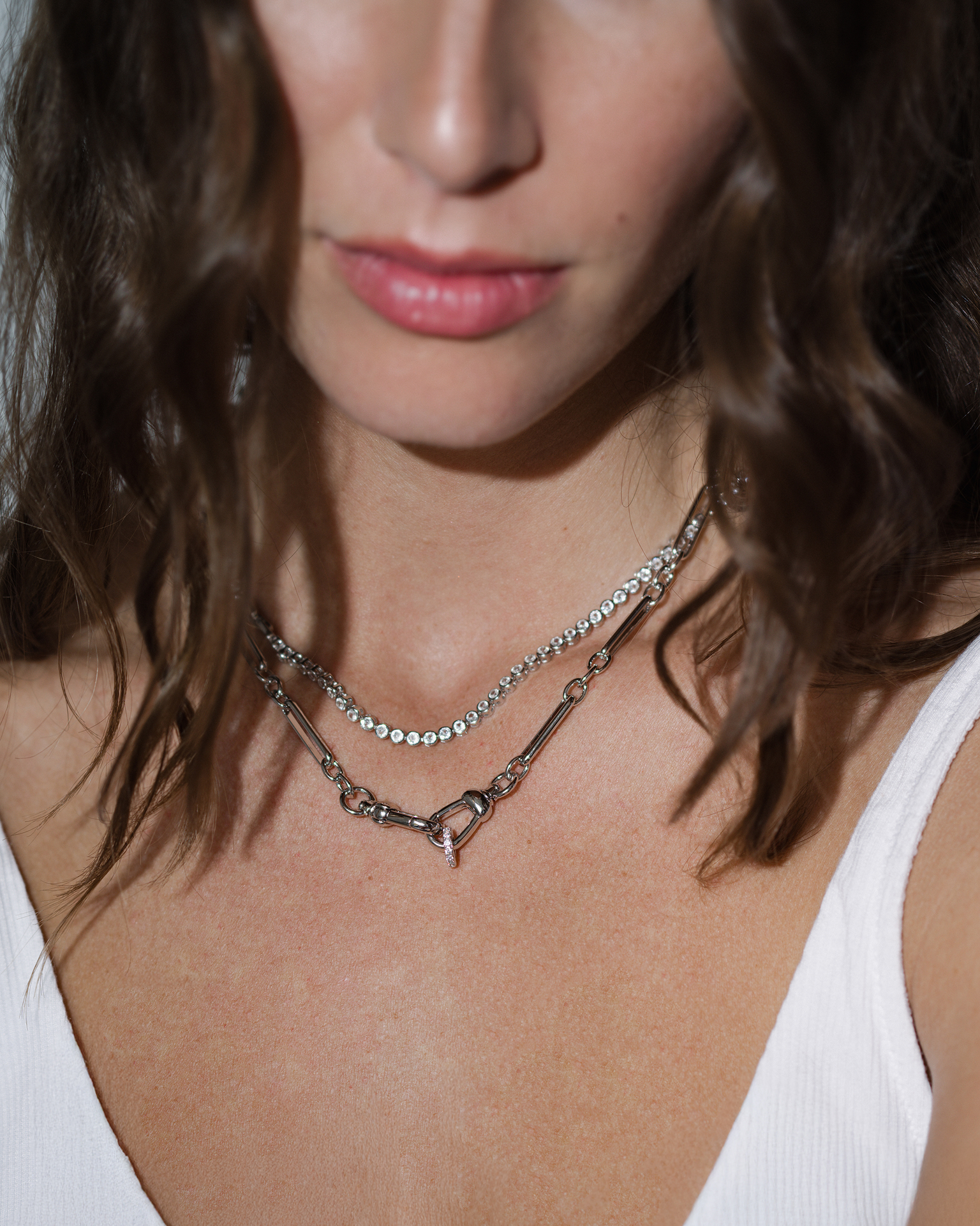 Close-up of a woman wearing a delicate necklace with a white top.