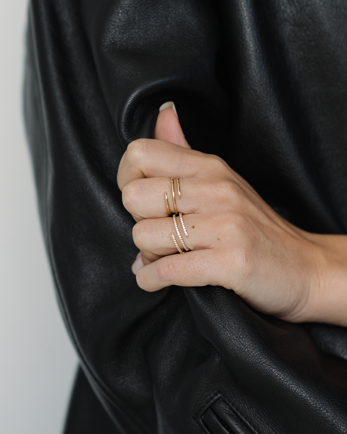 Hand wearing Greer Pave Spiral Ring on black leather jacket. Jewelry fashion shot showcasing statement ring.
