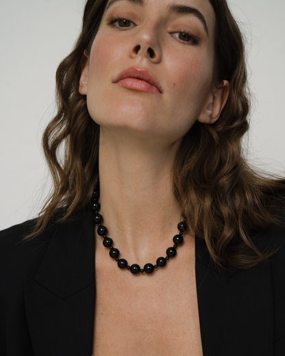 Woman wearing a Portia gemstone necklace, showcasing its elegant design and beaded detail against a black blazer.
