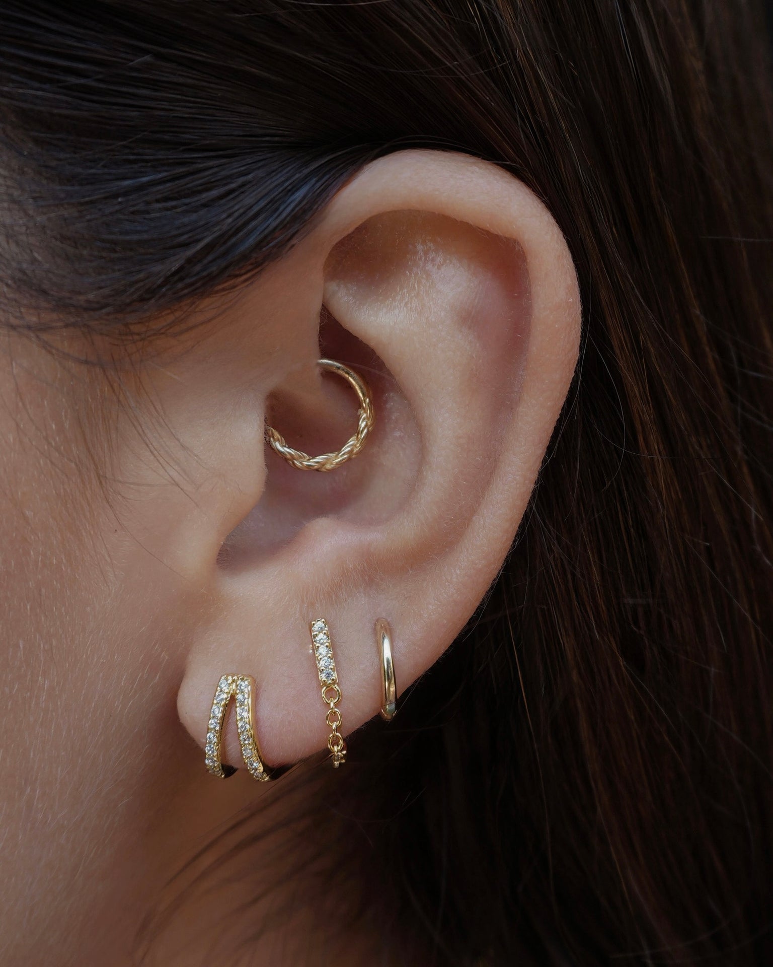 Close-up of ear showcasing Malia Double Pave Huggies and other earrings. Ear piercing jewelry.