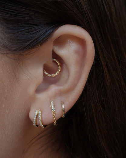 Close-up of ear showcasing Malia Double Pave Huggies and other earrings. Ear piercing jewelry.