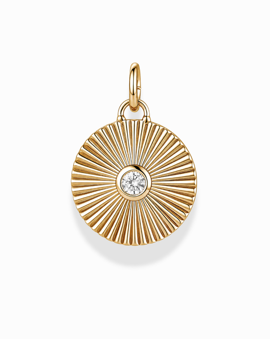 The Astra Fluted Charm by Mod + Jo features a radiating grooved design in 14k gold plating, accented with a bezel-set crystal at the center. This simple yet elegant charm comes with a small top loop for easy attachment to your favorite necklace, and is photographed on a clean white background.