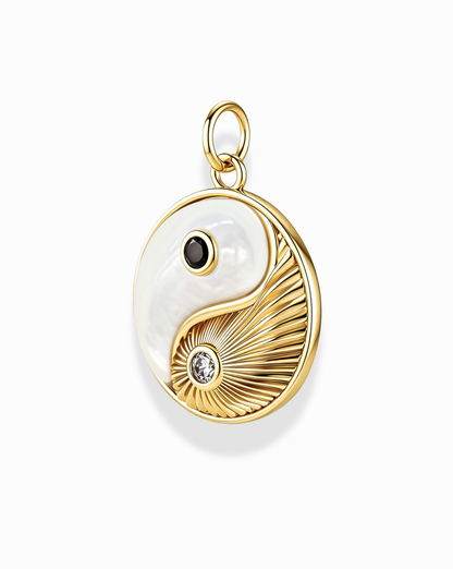 The Grande Ava Yin Yang Charm by Mod + Jo is an elegant 14k gold pendant featuring a gold and white yin-yang design with a black dot, clear gemstone, and textured gold lines set against a mother-of-pearl background—perfect for adding a refined touch to any necklace collection.