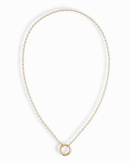 The Callum Tennis Charm Clip Necklace by Mod + Jo features a dainty gold-plated chain with a small circular pendant, elegantly displayed on a white background.