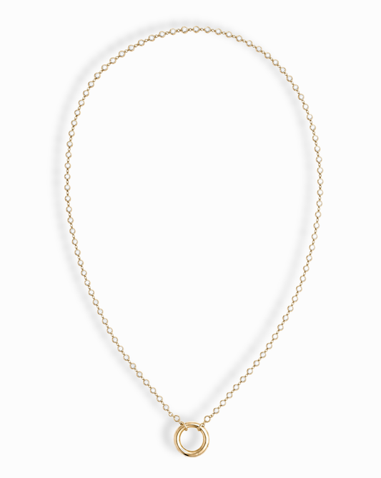 The Callum Tennis Charm Clip Necklace by Mod + Jo features a dainty gold-plated chain with a small circular pendant, elegantly displayed on a white background.