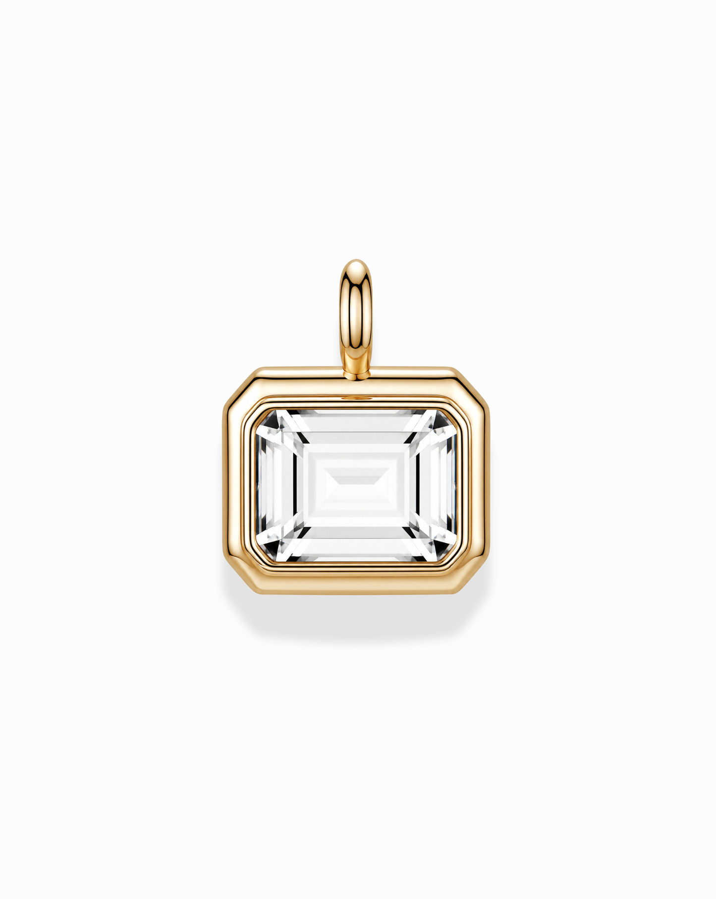 The Elsie Sapphire Bezel Charm by Mod + Jo features a rectangular, emerald cut lab-grown white sapphire set in a 14k gold bezel with a gold bail, showcased on a white background.