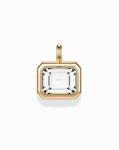 The Elsie Sapphire Bezel Charm by Mod + Jo features a rectangular, emerald cut lab-grown white sapphire set in a 14k gold bezel with a gold bail, showcased on a white background.