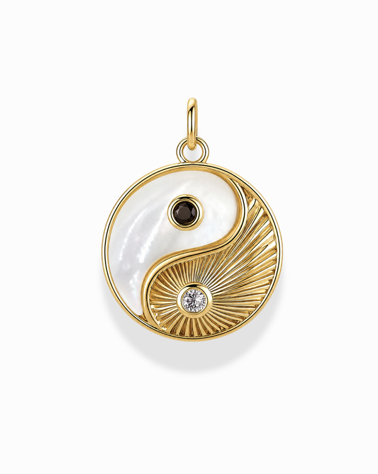 Introducing the Grande Ava Yin Yang Charm by Mod + Jo—a stunning 14k gold round pendant displaying a stylish yin-yang design in white and textured gold. Each half is adorned with a small black stone and a clear stone, effortlessly merging classic symbolism with modern elegance. This charm is an ideal statement piece or the perfect addition to your favorite mother-of-pearl necklace.