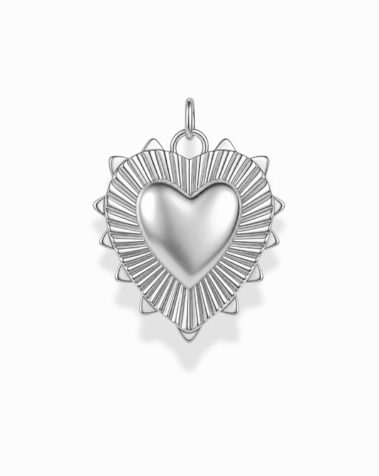 The Grande Lynn Engravable Heart Charm by Mod + Jo features a silver, heart-shaped pendant with a smooth center that’s perfect for personal engraving. The charm is accented by a textured border and delicate triangular rays inspired by the look of fine 14k gold jewelry, beautifully displayed against a white background.