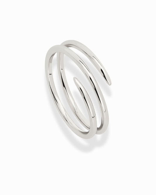The Greer Spiral Ring features a shiny silver, minimalist design with two smooth, open-ended coils. This stackable ring is spiral-shaped and photographed on a white background.