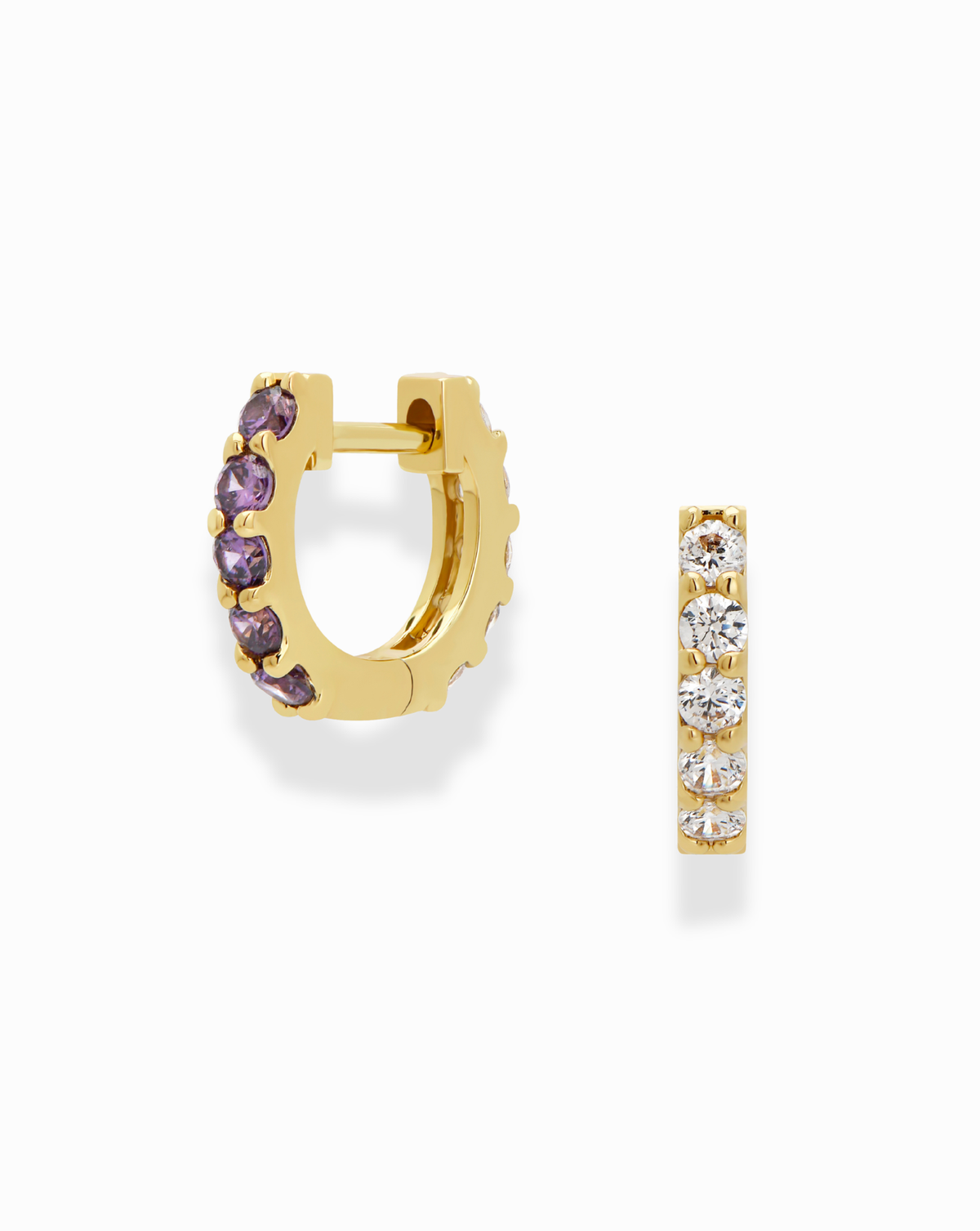 The Harlow Reversible Birthstone Huggies by Mod + Jo are gold plated hoops, featuring purple gems on one side and clear stones on the other—wear them either way for a versatile, stylish look. Shown on a white background.
