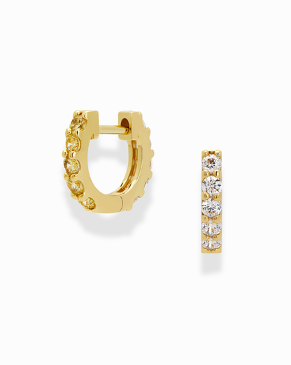 The Harlow Reversible Birthstone Huggies by Mod + Jo are small gold plated hoops with round white gemstones along the front, shown in side and front views on a white background.