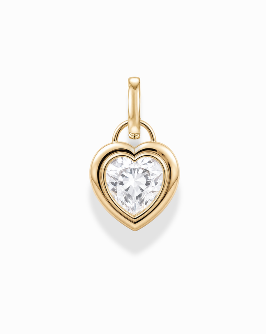 The Mod + Jo Jovie Sapphire Heart Charm is a 14k gold pendant with a large, round-cut lab-grown white sapphire at its center, displayed against a white background.
