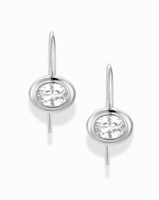 Silver earrings with bezel oval sapphire gemstones on a white background