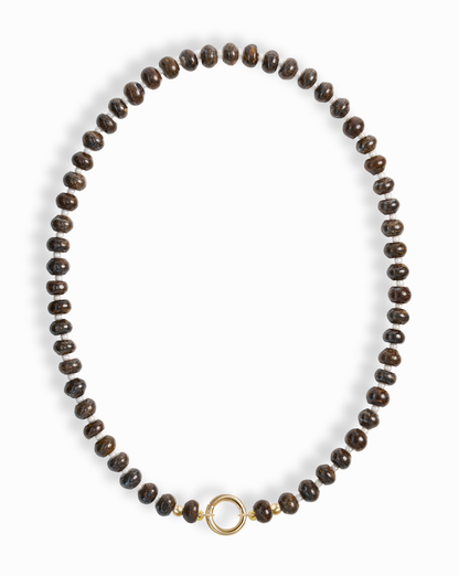 The Macey Gemstone Necklace by Mod + Jo features evenly spaced dark brown round beads and a simple 14k gold-plated circular clasp at the center, displayed on a white background.