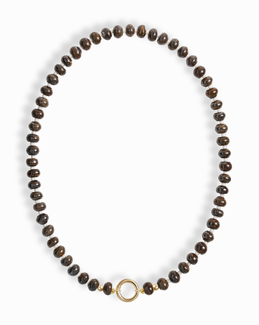 The Macey Gemstone Necklace by Mod + Jo features evenly spaced dark brown round beads and a simple 14k gold-plated circular clasp at the center, displayed on a white background.