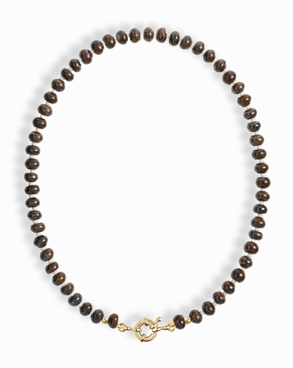 The Mod + Jo Macey Gemstone Necklace features round, dark brown genuine gemstones and a 14k gold-plated clasp, elegantly arranged in an oval shape on a white background.