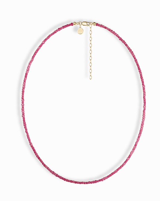 The Merit Gemstone Necklace features small pink beads, a 14k gold-filled clasp, and an adjustable chain, shown on a white background.