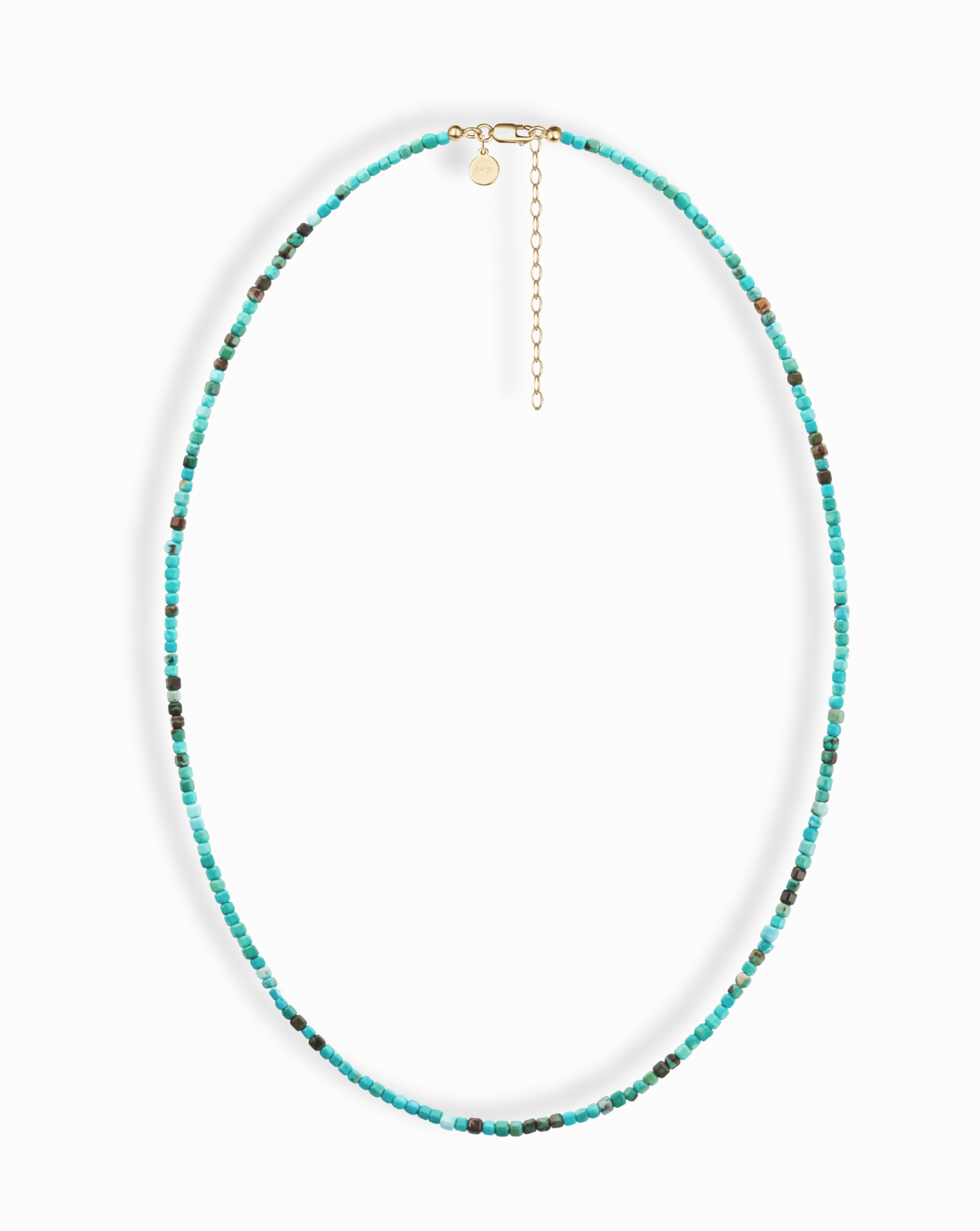 The Merit Gemstone Necklace by Mod + Jo features small, round turquoise beads with subtle color variations, a gold clasp, an adjustable chain, and a small round charm.