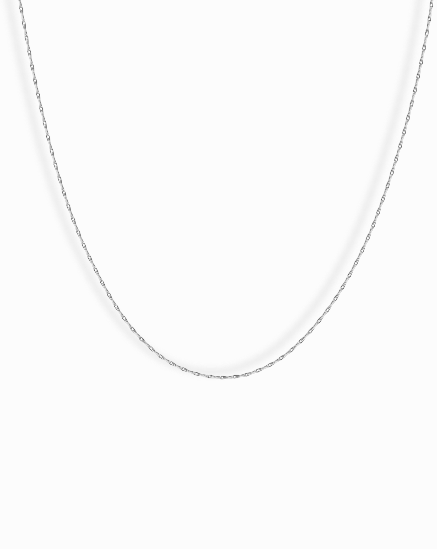 The Odette Barley Chain Necklace, crafted from delicate sterling silver, is displayed against a plain white background, its thin barley chain forming a gentle curve.