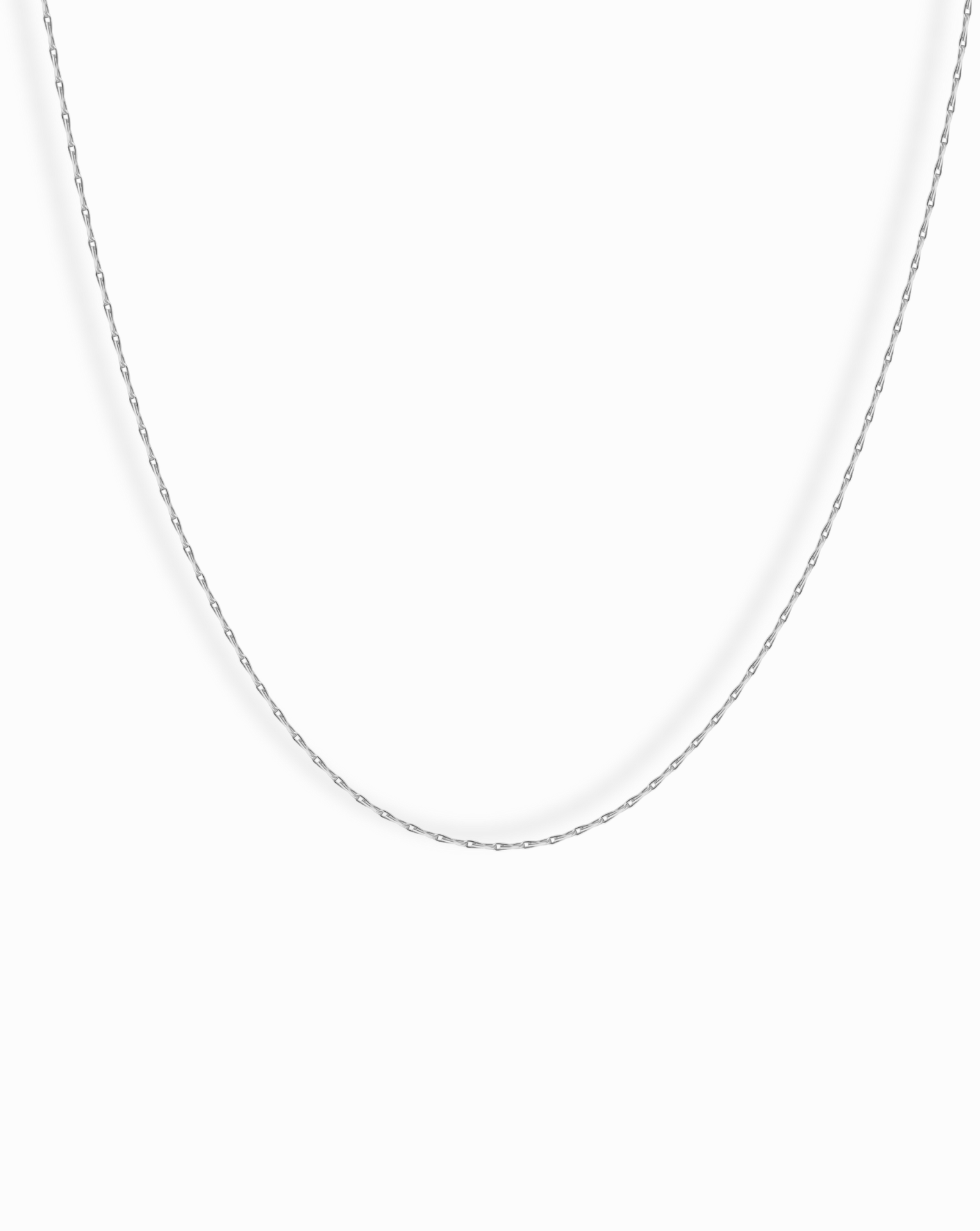 The Odette Barley Chain Necklace, crafted from delicate sterling silver, is displayed against a plain white background, its thin barley chain forming a gentle curve.