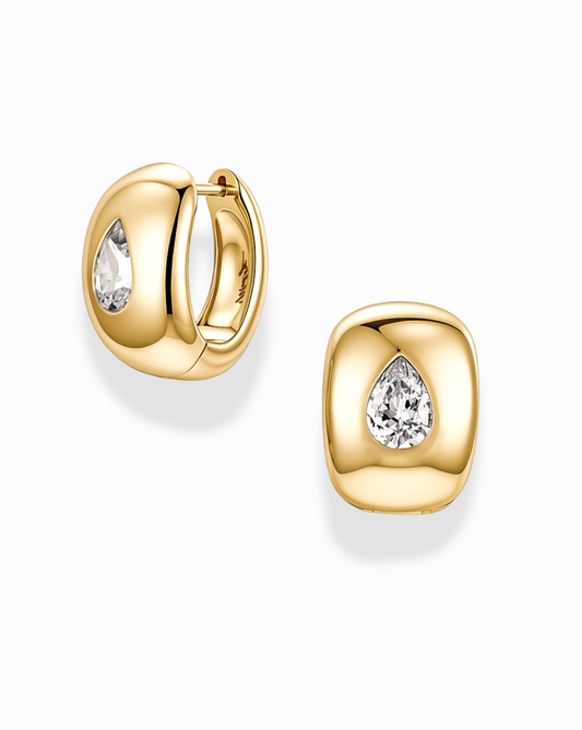 Introducing the Penn Gemstone Hoops by Mod + Jo: these polished, gold-plated brass earrings feature a rounded, cushion-like silhouette. Each hoop showcases a central pear-shaped clear gemstone surrounded by sparkling CZ accents and secures with a hinged closure.