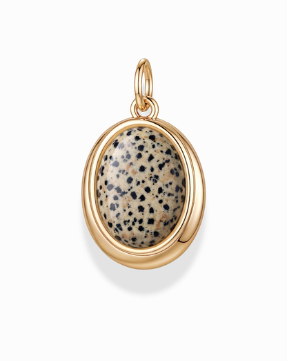 The Rory Gemstone Charm by Mod + Jo features an oval polished Dalmatian Jasper stone with a beige base and black spots, set in a smooth 14k gold over brass bezel with a top loop for easy attachment to a necklace.