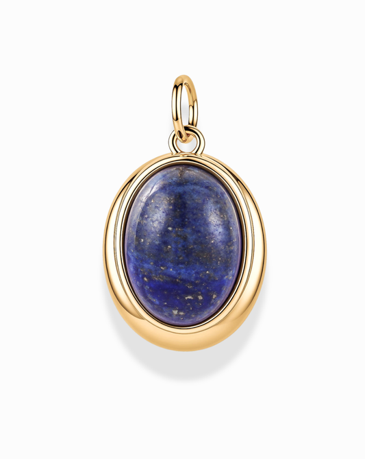The Rory Gemstone Charm by Mod + Jo showcases a polished dark blue gemstone with delicate gold flecks, artfully set in an oval design with a 14k gold over brass frame for a timeless and elegant appearance, reminiscent of classic lapis lazuli jewelry. Presented against a plain white background.