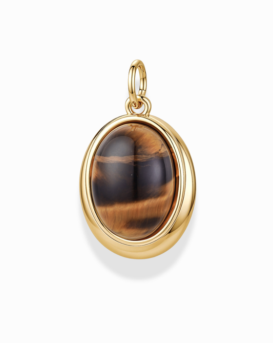 Introducing the Rory Gemstone Charm by Mod + Jo—a stunning gold-plated pendant showcasing an oval Tiger’s Eye gemstone with mesmerizing brown and golden bands. This exquisite piece is set in a polished 14k gold bezel with a convenient loop for your favorite chain, elegantly displayed against a white background. The Rory Gemstone Charm beautifully captures the natural allure of Tiger’s Eye, making it a standout addition to any jewelry collection.
