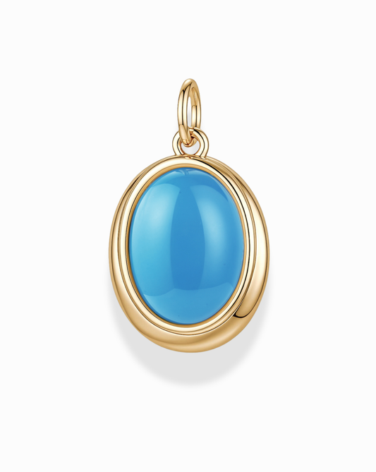 The Rory Gemstone Charm by Mod + Jo features a smooth, oval-shaped bright blue turquoise gemstone set in a gold bezel with a loop at the top for attaching to a chain. This elegant piece of jewelry is displayed against a white background.