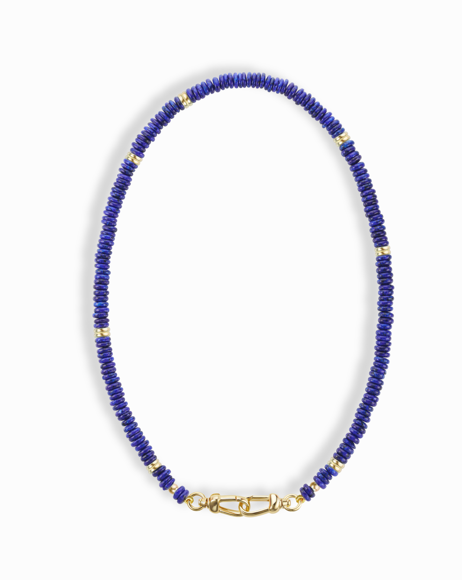 The Sonia Gemstone Necklace by Mod + Jo features small, round blue lapis lazuli beads with gold spacer beads and a gold clasp, displayed in an oval shape on a white background.