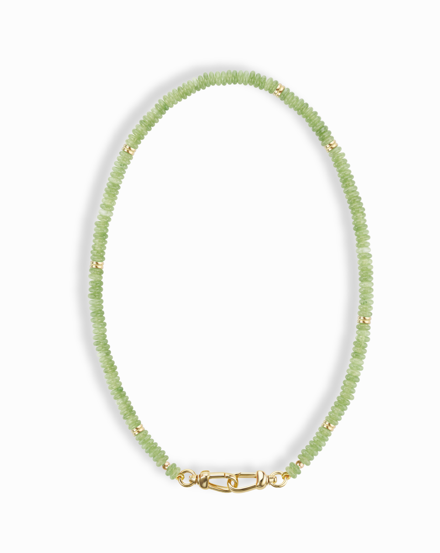 The Sonia Gemstone Necklace by Mod + Jo features small, round, light green genuine gemstone beads with gold spacers and a gold clasp, elegantly arranged in an oval shape against a white background.