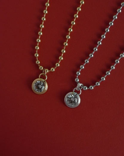Two necklaces with round pendants on a red background