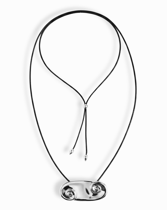 The Suna Spiral Cord Necklace by Mod + Jo features a black cord with sculptural polished silver double-spiral pendants and modern silver tips. The adjustable design offers a contemporary, stylish look.