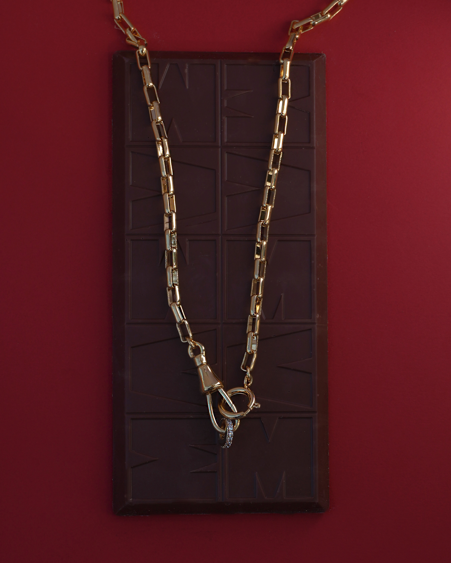 gold chain necklace draped over a chocolate bar