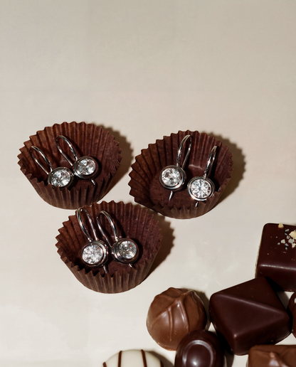 earrings in a little chocolate wrappers with additional chocolates on a beige background